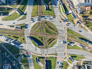 Traffic circle Rondo Czyzynskie in Krakow, Poland, with tramway crossing, three trams, three lane city roads, bicycle lanes, underground pedestrian crossings and cars. Aerial view from above - 700117749