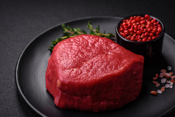 Fresh juicy raw filet mignon with salt, spices and herbs