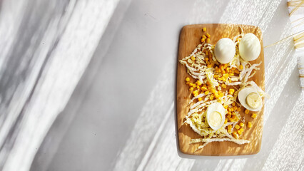 Chopped Peking cabbage, peeled eggs and yellow canned corn on cutting board as a background. Cooking a healthy eco-friendly salad from natural products. Copy space and place for text