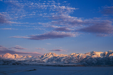 winter landscape with the Tien Shan mountains in Kazakhstan in the snow in the steppe under a blue sky with clouds at sunset