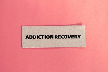 Obraz premium Addiction recovery lettering on ripped paper piece with color background. Conceptual photo. Top view, copy space.