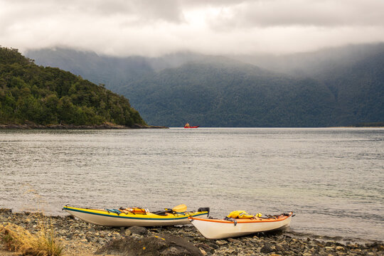 sea kayaks  on a beach in the chonos archipelago, patagonia, chile with sea and mountains in backbground room for text