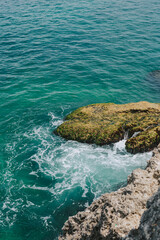 Rocky beautiful shore against the background of waves and sea foam.