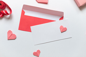 Red paper envelope with white blanks and pink origami hearts. Valentine's day concept card. Copy...