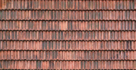 Close up of red terracotta roof shingles with some mildew. Background texture of old roofing material