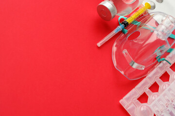 Coronavirus treatment concept. A medical face mask nebulizer for treatment of respiratory tract and packs of ampoules flat layed on red background. Copy space