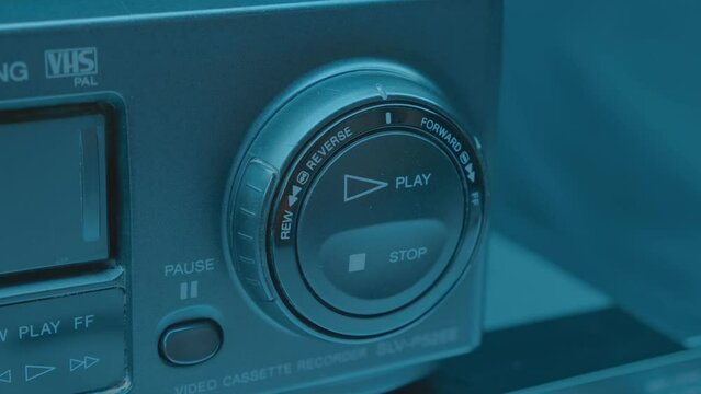 A man's finger presses the play, stop button / forward, reverse knob on a black home VCR to watch his favorite movie. Closeup. Macro. Shot in motion
