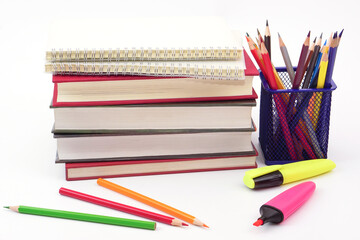 Fototapeta premium Crayon or colored pencils in box with side stack of books and school supplies on with background. Learning, study and office equipment concept.
