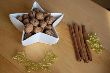 Christmas still life with walnuts in white bowl, golden thin wire stars and cinnamon bark...