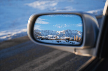 reflection of a beautiful winter landscape with mountains and village in the snow in rearview...