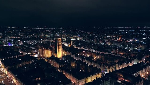 A mesmerizing drone film captures Gdańsk's city center at night in December. Glowing city lights and moving cars create a festive urban scene.