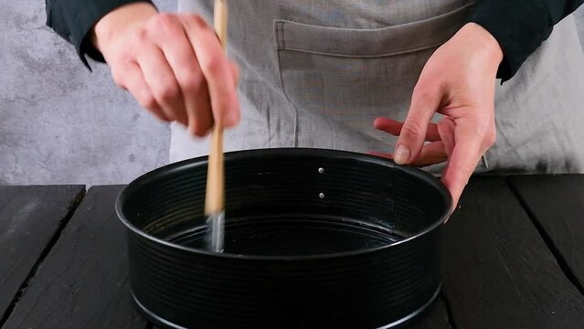 Young woman's hands holding baking mold and greasing it with butter. Dough, baking, homemade cooking. Close-up of pan