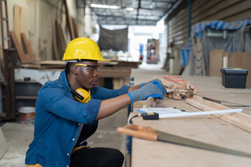 Male carpenter working in wood processing plants. Black male carpenter working at wood workshop. Concept of wood industrial factory