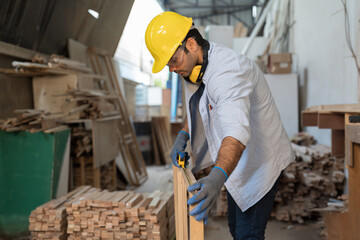 Male carpenter checking piece of wood. Builder worker working with wood. Male construct making...