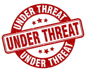 under threat stamp. under threat label. round grunge sign