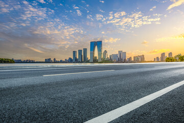 Empty asphalt road and city buildings skyline at sunset in Suzhou