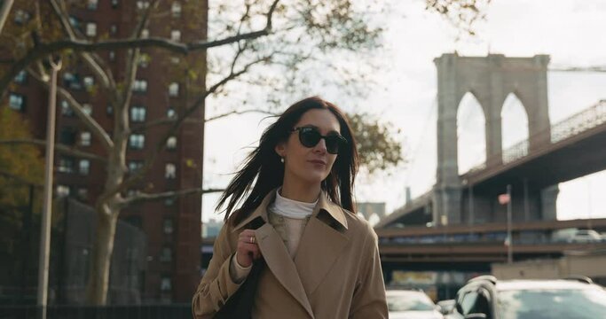 Free and happy attractive female enjoying walking in New York streets with the iconic Brooklyn Bridge in the back