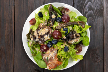 Green salad, berry with crispy fried salmon skin. Healthy and balanced menu.