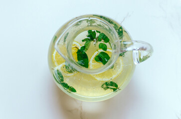 High angle view of pitcher of mint lemonade on marble table