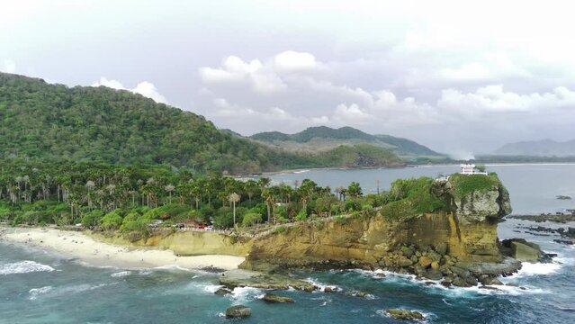 Aerial shot on Papuma Beach, Jember, Indonesia with thick vegetations and towering iconic cliff on the ocean.