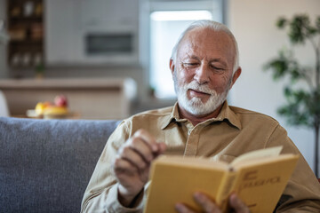 Senior men enjoying time at home by reading his favorite book.