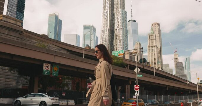 Cinematic shot of young stylish female walking against the vibrant backdrop of Manhattan cityscape