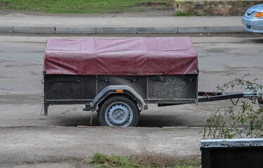 There is a car trailer covered with an awning on the side of the road. cargo trailer for a...