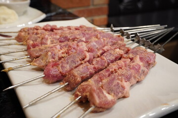 Raw, uncooked lamb skewers are served.