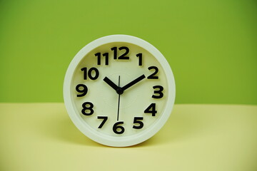 Fototapeta na wymiar White alarm clock with space copy on green and yellow background