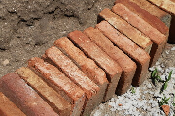 Close up of  bricks.  Row of red clay bricks on construction site. Construction material for houses and buildings. Concept of masonry, housing, real estate, construction.