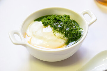 Greek yogurt and wolffia globosa in ceramic bowl isolated on white table background. Wolffia is the...
