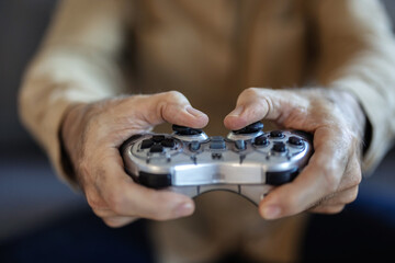 Senior man playing video game using virtual reality goggles at home. Senior man on couch, playing a VR game.