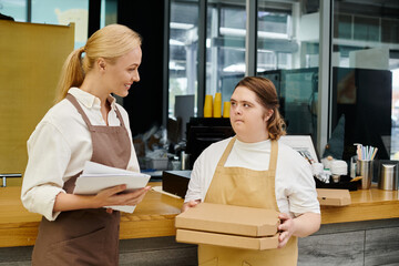 young woman with mental disability holding pizza boxes near smiling manager in modern cafe