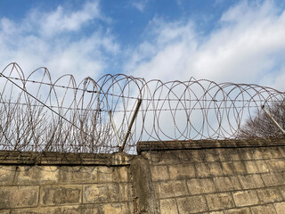 
Wall, barbed wire and blue sky, close-up