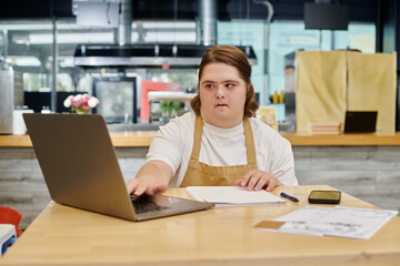 young woman with mental disorder working on laptop near smartphone on table in modern cafe