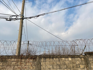 Walls, barbed wire, electric poles, electric lines, blue sky,