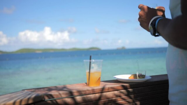 Man eating Caribbean food in front of the sea