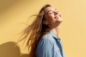 portrait of a happy young woman of model appearance in profile with long luxurious hair on a bright yellow background. The sphere of beauty and fashion