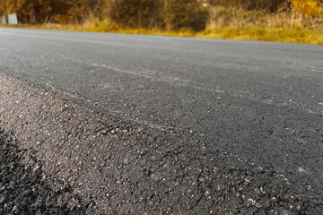 The close-up texture of the fresh hot asphalt on the new road. Road construction. A large layer of...