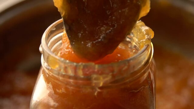Close-up spoon picks up cooked orange jam from pan. High quality FullHD footage