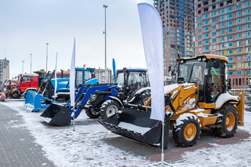 Two wheeled tractors, a bulldozer and snow removal machinery at an industrial exhibition in winter