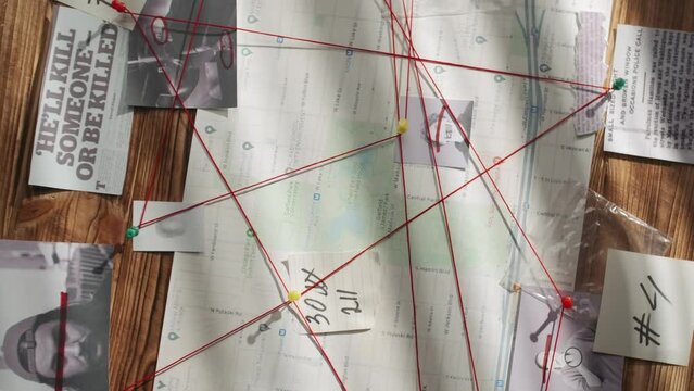 Close up shot of investigation board. Detective board with pieces of newspapers, killer photographs, map and red thread connecting clue proofs.