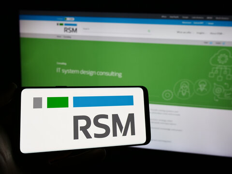 Stuttgart, Germany - 12-20-2023: Person holding mobile phone with logo of global accounting company RSM International Ltd. in front of business web page. Focus on phone display.