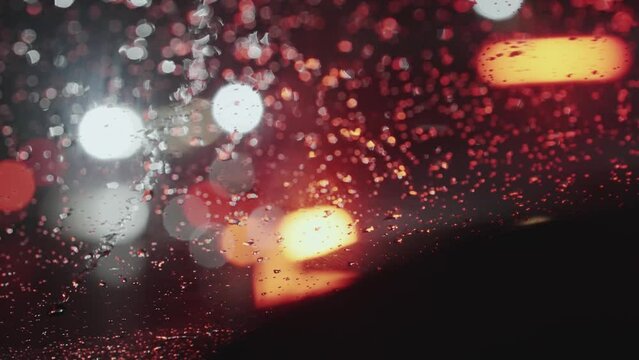 Bokeh blurry traffic lights on city street road through car window at night