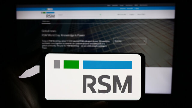 Stuttgart, Germany - 12-20-2023: Person holding smartphone with logo of global accounting company RSM International Ltd. in front of website. Focus on phone display.