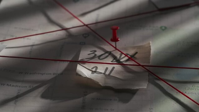 Close up shot of investigation board. Detective board with map of crime scene, pinned note with numbers and red thread connecting clue proofs.