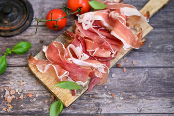 Slices Of  Traditional Italian antipasti  Prosciutto Crudo on a wooden  cutting board .Raw ham