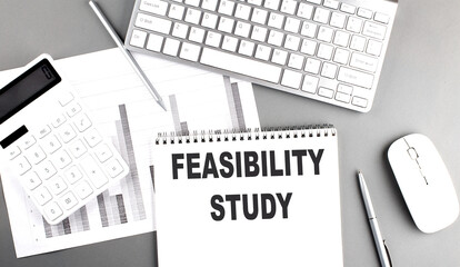 FEASIBILITY STUDY text written on a notebook on grey background with chart and keyboard, business...