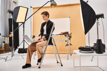 gorgeous short haired photographer sitting and retouching photos in her studio using her laptop