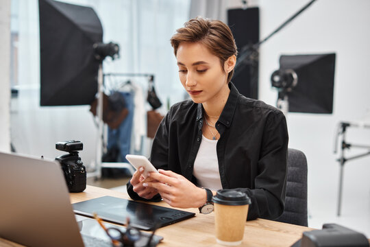 attractive young short haired woman with smartphone in her hands while working in photo studio
